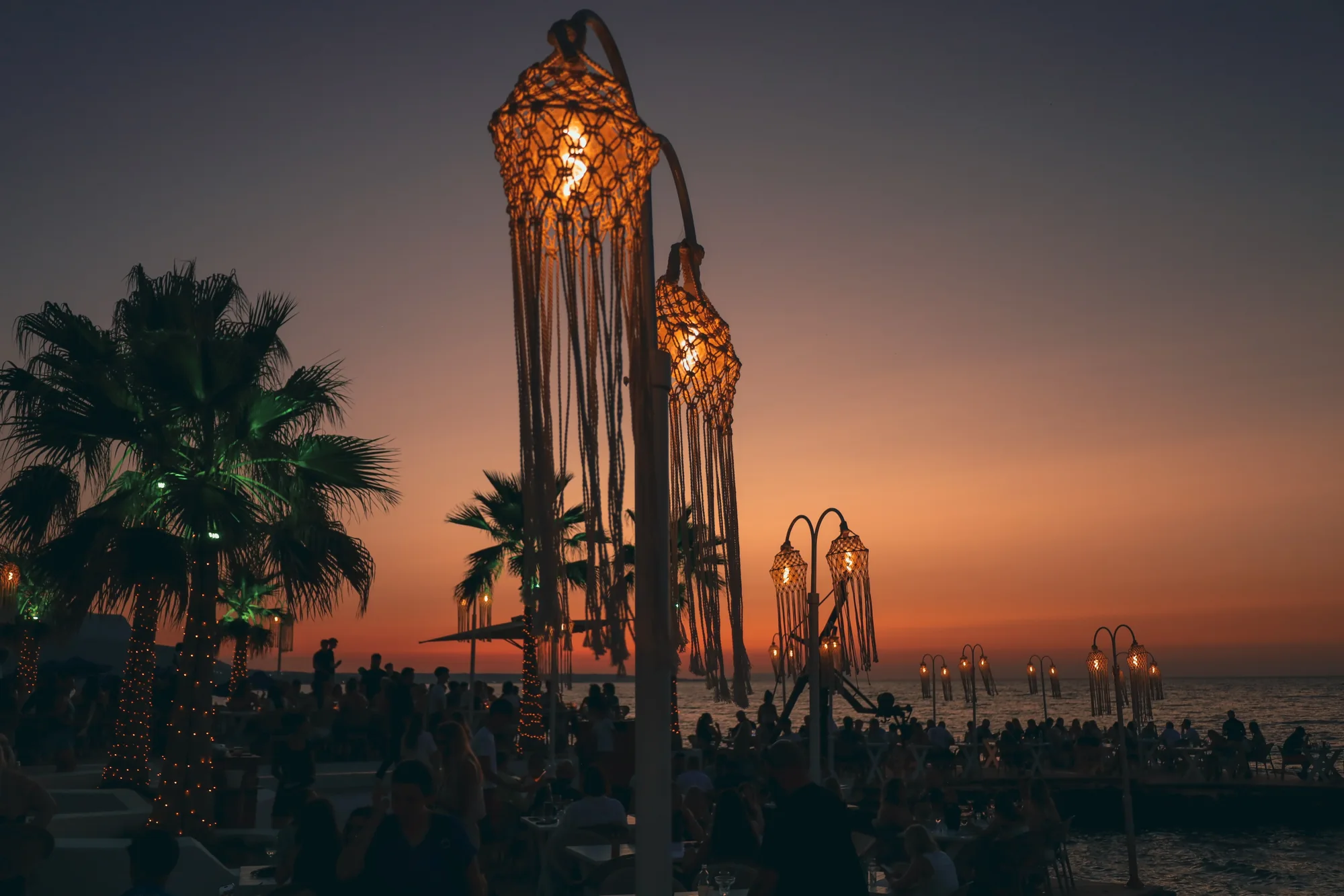 Glowing macramé lanterns over Thalassa’s waterfront terrace at sunset