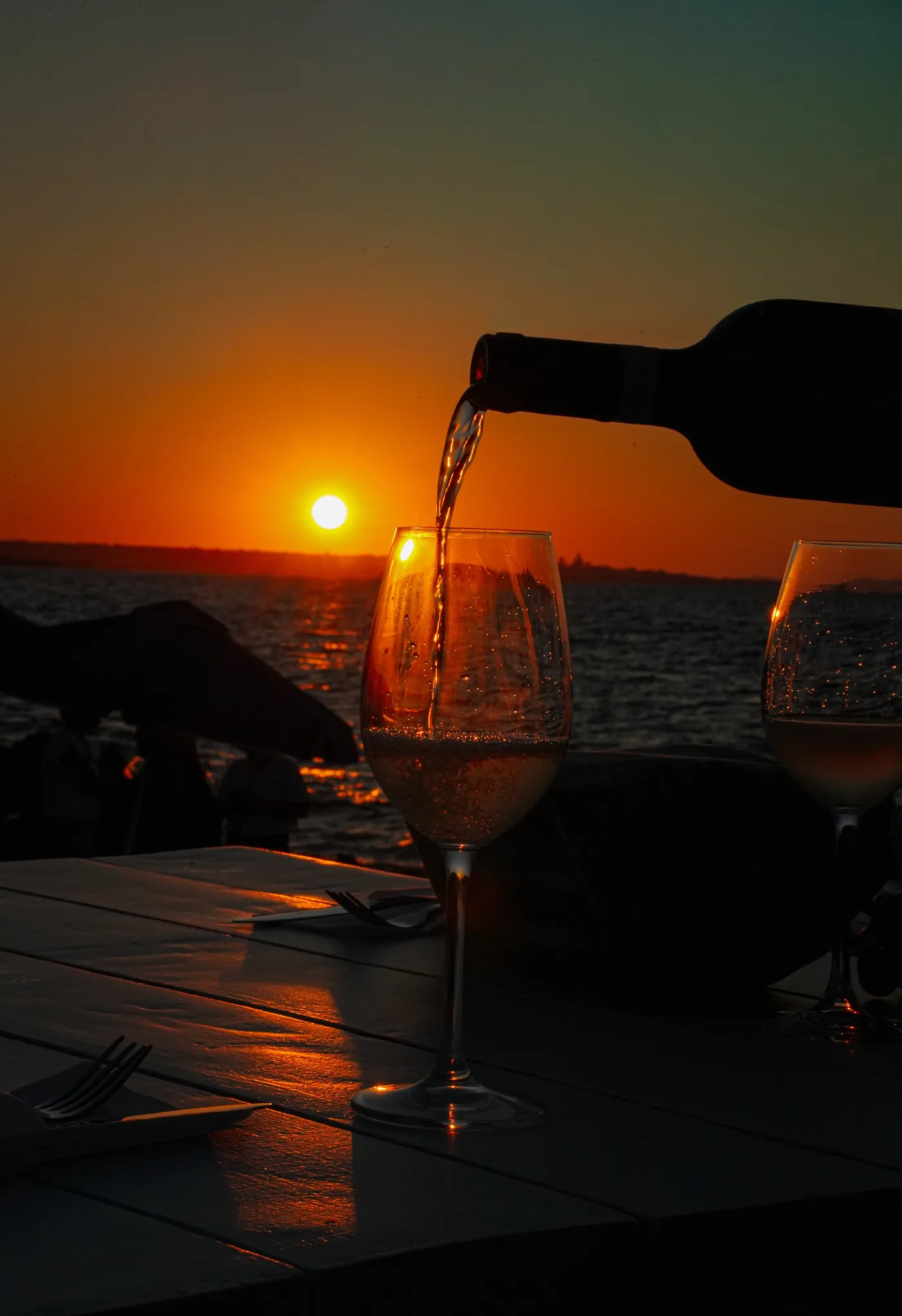 A cocktail being poured in front of the sunset